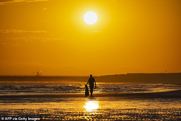 A French police officers carries a migrant's jacket during a patrol on Gravelines beach