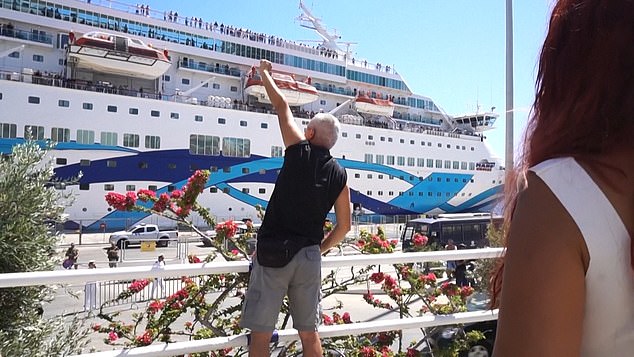A protester greets the passengers on the deck of the cruise ship