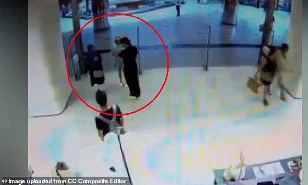 A Zara staff member (right of red circle) eventually approaches and leads Ms Nelmes (blue dress) and another woman (left of red circle) back inside the store