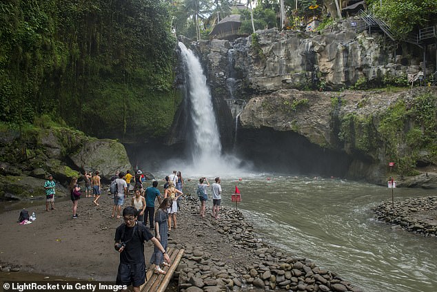 Over-commercialisation has led to what some describe as aggressive touting and inflated prices near temples, markets and popular nature spots. Pictured: Tourists at the Tegenungan Waterfall