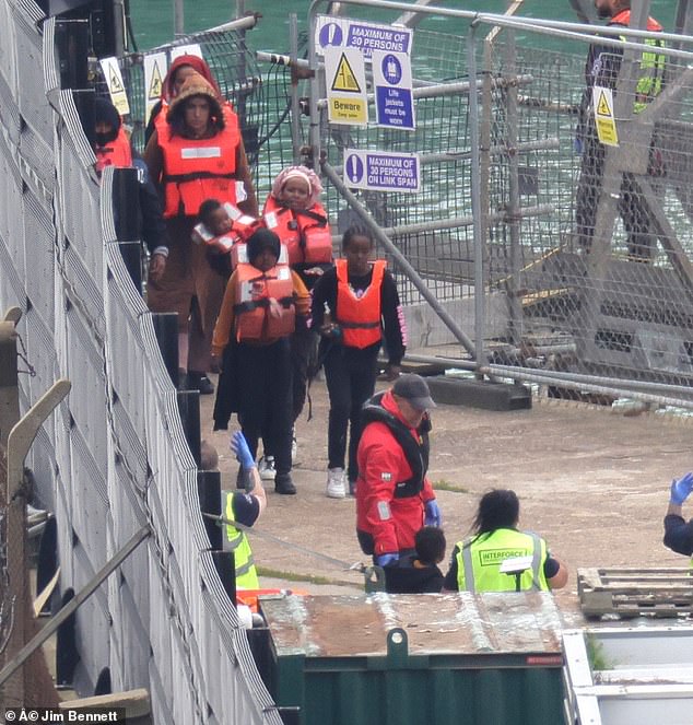 Migrants being escorted into Dover after crossing the channel on a boat