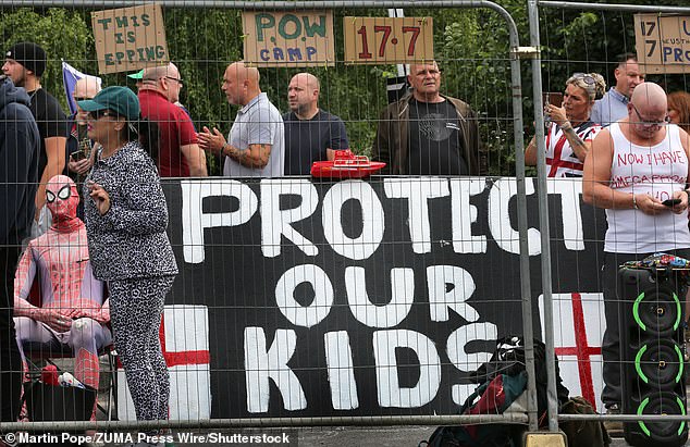Anti-migrant protesters hold up signs outside an asylums seeker hotel in Epping