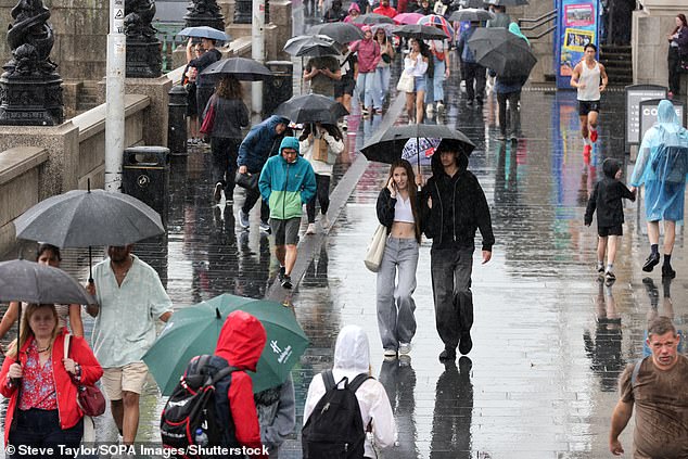 The warning runs from 10am until 9pm Thursday (pictured: tourists sheltering under umbrellas earlier this month in London)