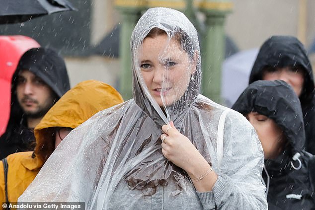 A woman covers her head with a poncho in London after rain hit the country earlier this month