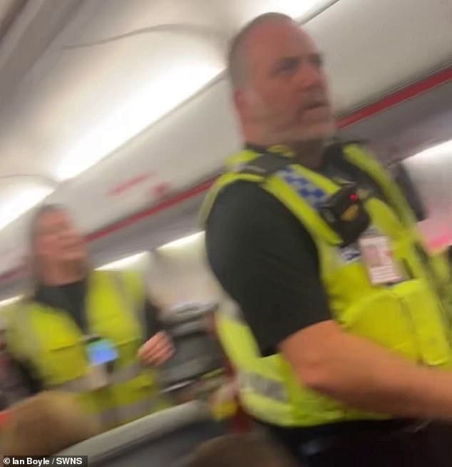 Footage shows a burly policeman walk down the aisle to confront the pair