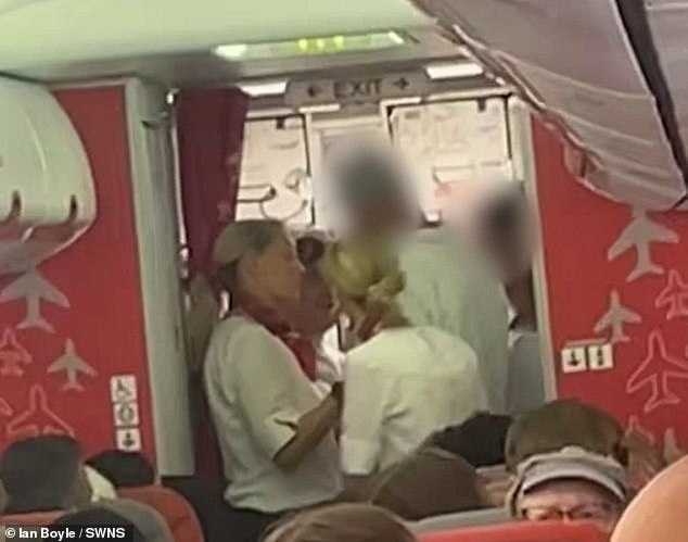 A distressed female cabin crew member is later filmed in the middle of an altercation at the plane exit
