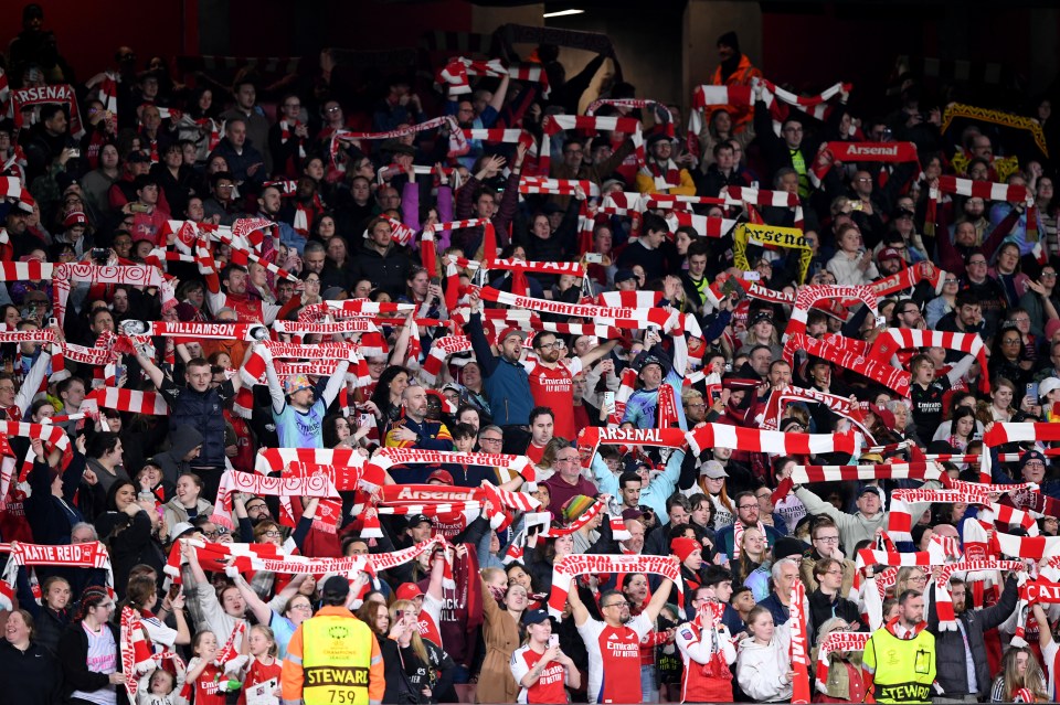 Arsenal fans holding up scarves at a match.