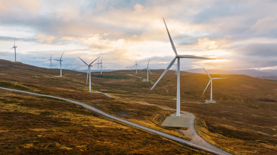 Aerial view of a wind farm on a Scottish hillside at sunset.