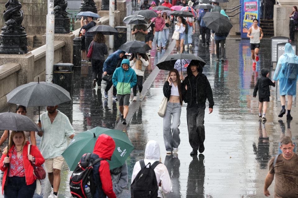 Tourists in Westminster sheltering under umbrellas in heavy rain.