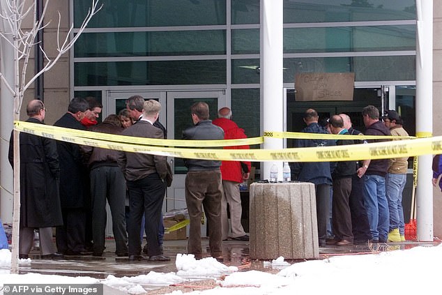 Police officers and officials stand in front of Columbine High School in April, 1999, where 13 students and one teacher were killed