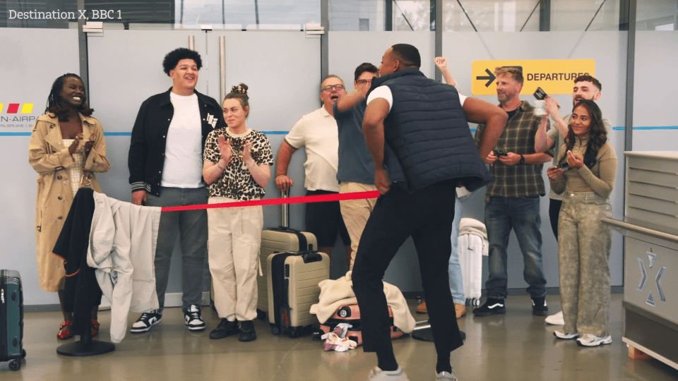 A group of people at an airport celebrating the opening of a new destination.
