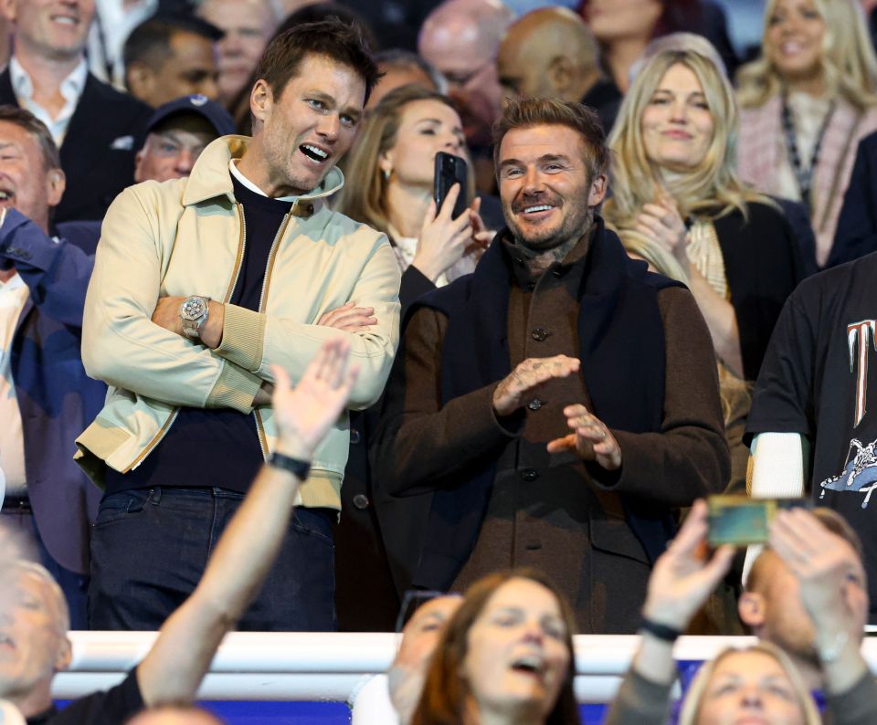 Tom Brady and David Beckham smiling in the stands at a football game.