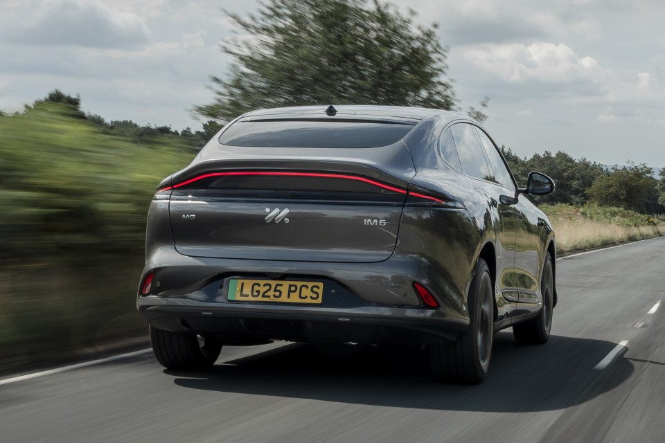 Rear view of a dark gray IM6 electric car driving on a road.