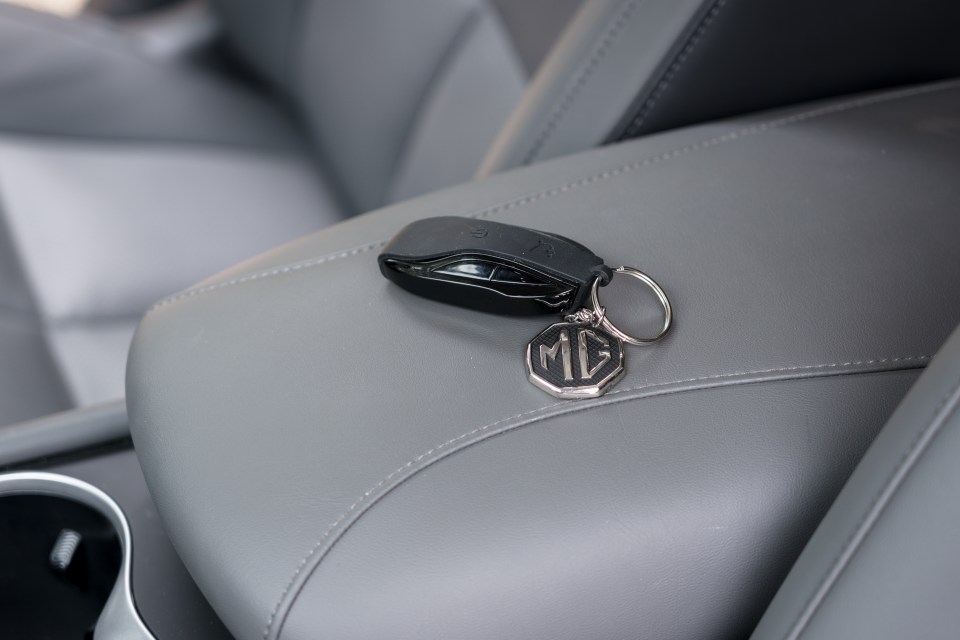 MG car key on grey leather car seat.