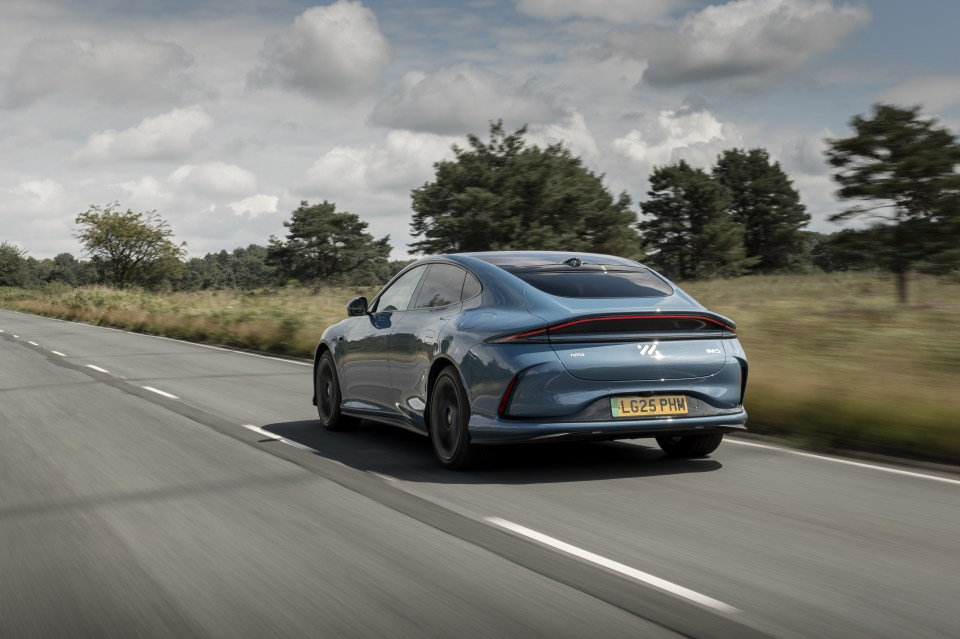 Rear view of a blue MG5 EV driving on a road.