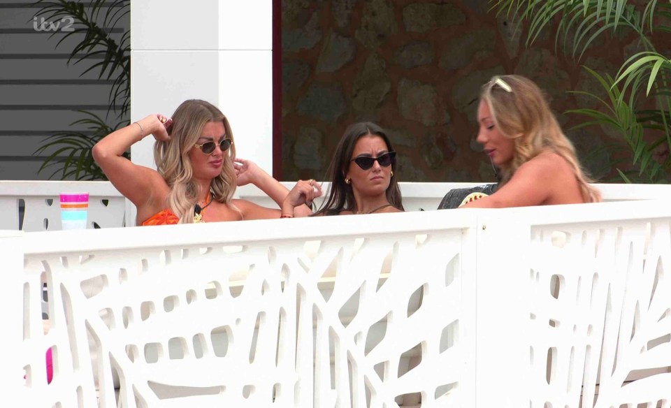 Three women talking on a balcony.