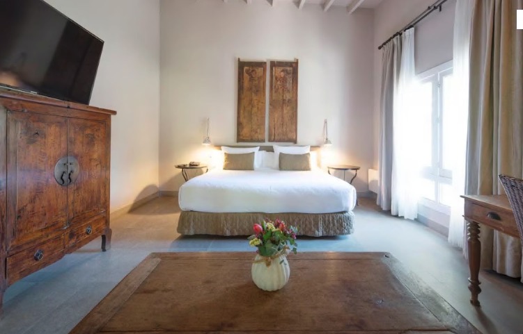 Hotel room with king-size bed and antique furniture.