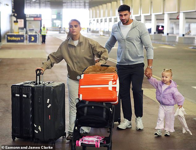 The influencer had her hands full with Bambi's empty pushchair and the family luggage while Tommy Fury walked hand-in-hand with their young daughter at Manchester Airport