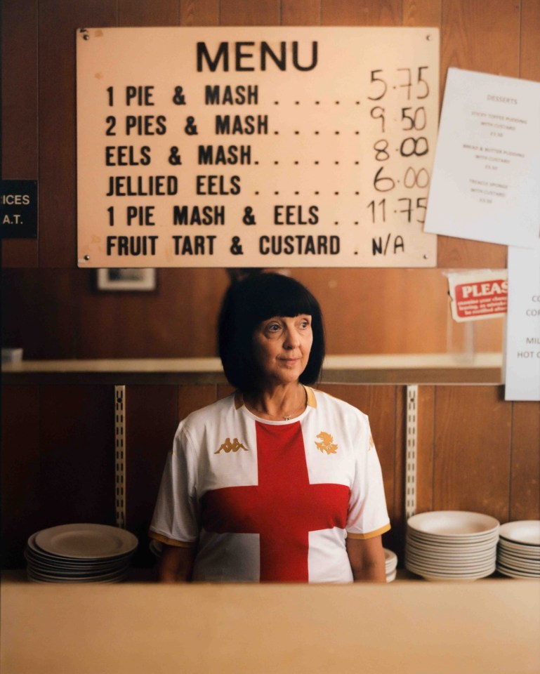 Woman in Genoa soccer jersey standing behind a counter with a menu.