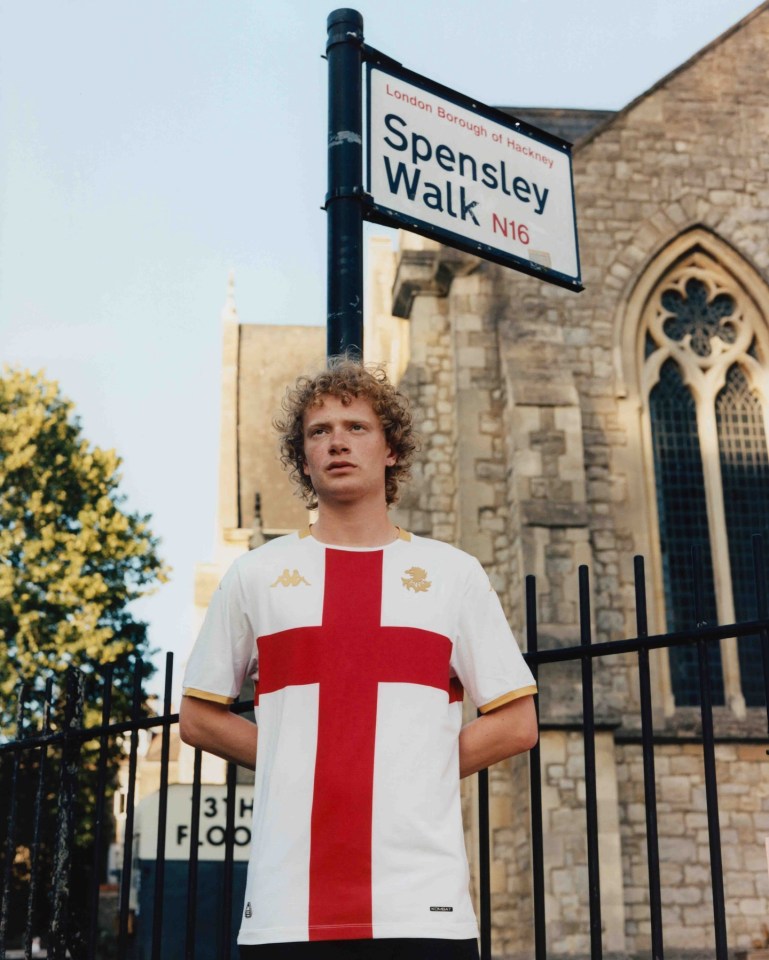 Person wearing a Genoa soccer jersey in front of a church.