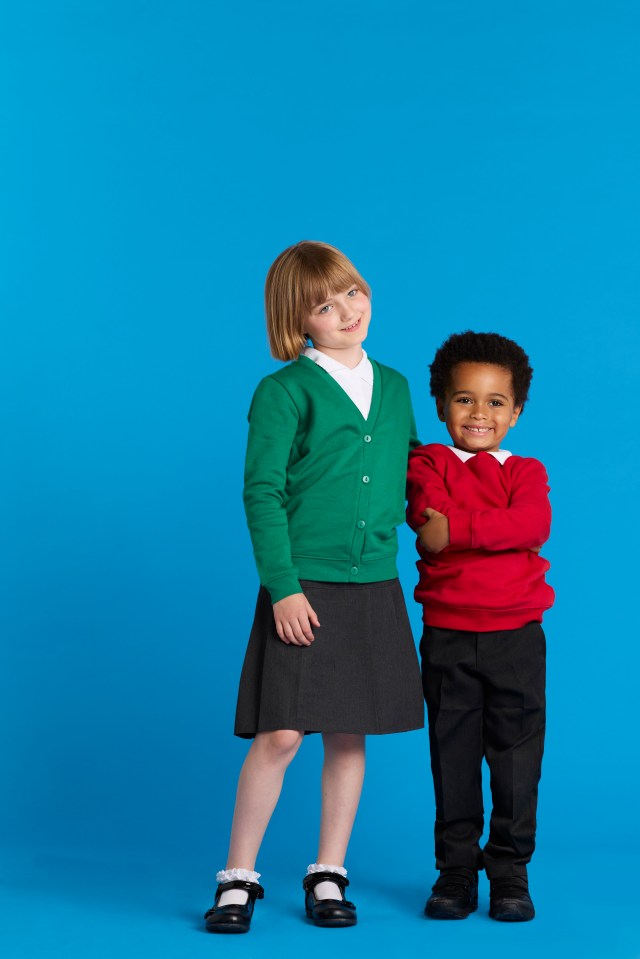 Two children in school uniforms stand together against a blue background.