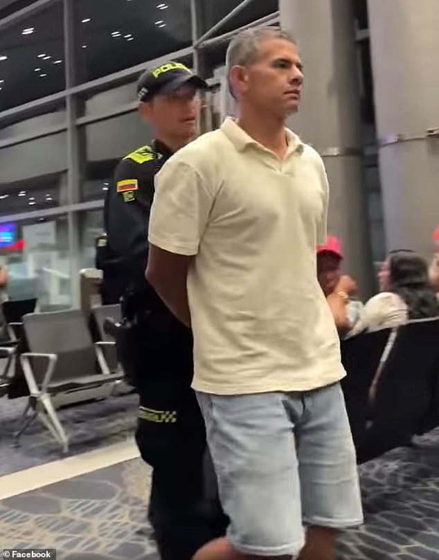 A police officer escorts Santacruz after he assaulted the female passenger