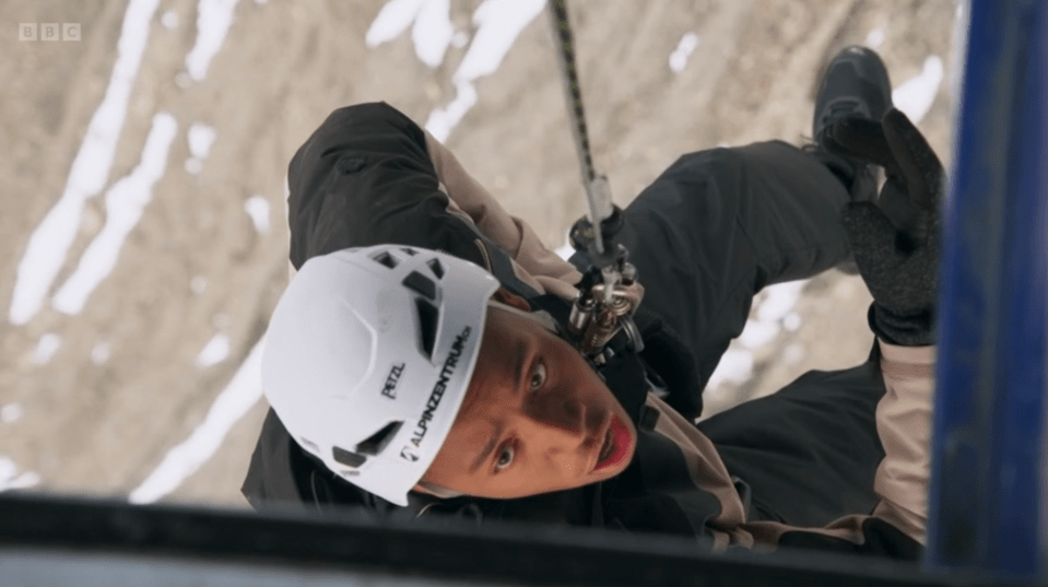 Person rappelling down a cliff face.