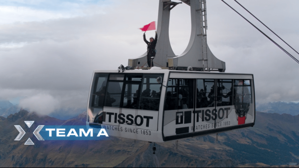 Team A's cable car over mountains; Tissot advertisement visible.