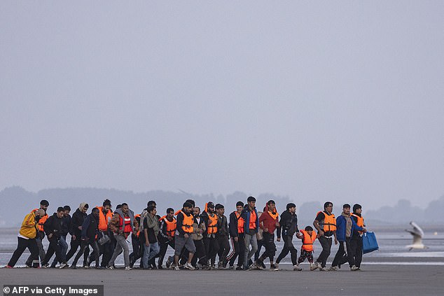 Migrants run to try to board a smuggler's inflatable dinghy in an attempt to cross the English Channel off the beach of Gravelines, northern France, on July 29, 2025