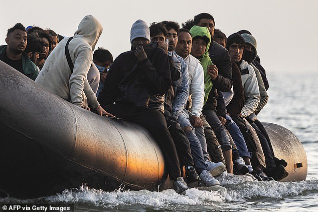 Migrants board a smuggler's inflatable dinghy in an attempt to cross the English Channel off the beach of Gravelines, northern France, on July 29, 2025