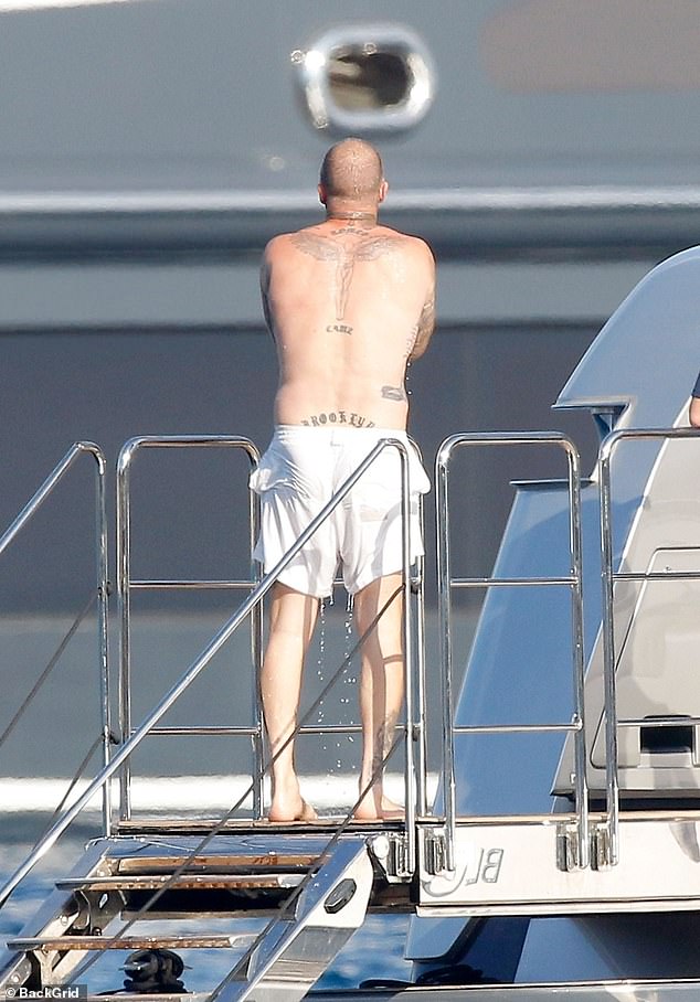 David put his tattooed frame on display as he used the outdoor shower on board the vessel after having a swim