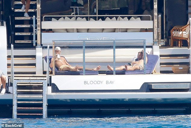 Romeo went shirtless as he sunbathed and enjoyed a cold drink with a friend during the trip