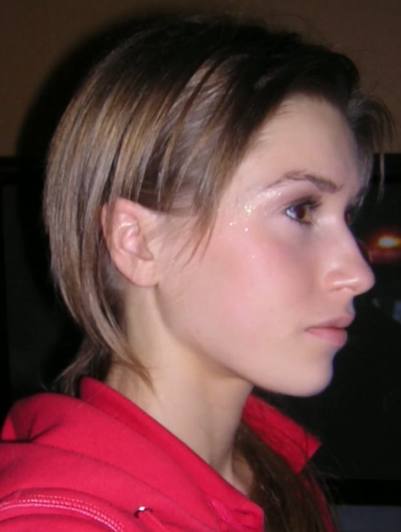 Profile view of a young woman with short brown hair wearing a red hoodie.