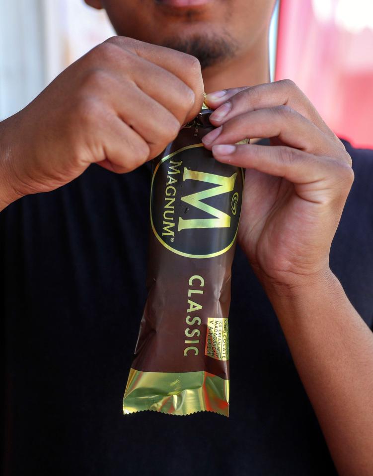 Person unwrapping a Magnum Classic ice cream bar.