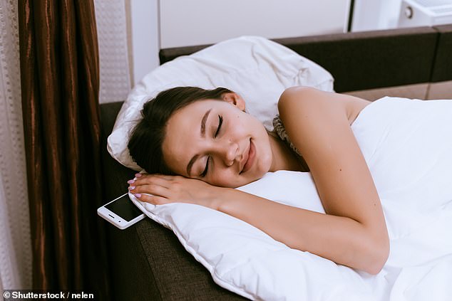 It might feel like a good idea to sleep with your phone close, but experts have warned that charging it under your pillow or a blanket could pose a fire safety risk (stock image)