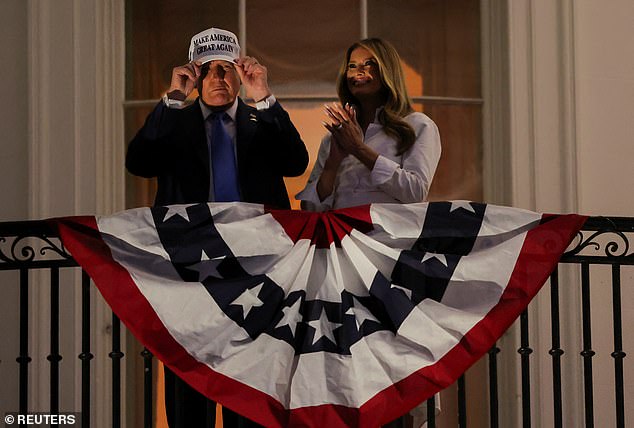 President Donald Trump (left) puts on a white Make America Great Again hat as he and first lady Melania Trump (right) watch the fireworks display over the National Mall on Friday to mark the Fourth of July