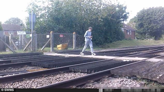 In one of the chilling clips released by Network Rail, a teenage boy is seen standing on the lines while gazing at his mobile, just moments before a train passes