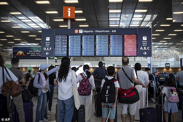 Passengers look a departures information board at Paris Orly Airport during the strike on July 4