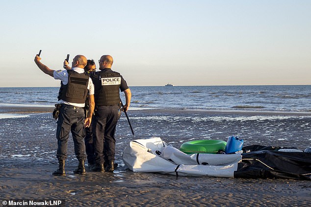 Calais police pose for a selfie after slashing a people smugglers' dinghy on Gravelines beach on Saturday