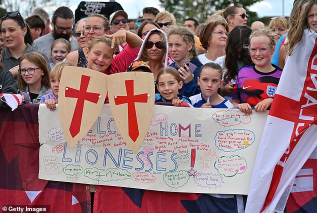 Fans with home-made signs wait for the team to arrive back in the UK