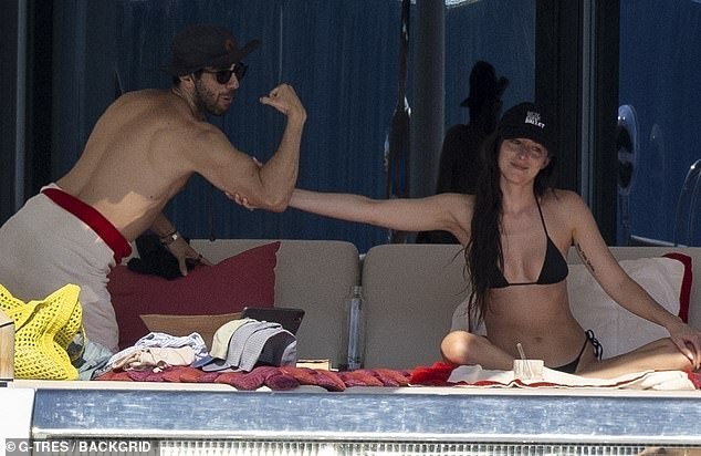 Dakota Johnson, 35, put on a flirty exchange with a mystery man as she spent time on a star-studded yacht in Ibiza this week