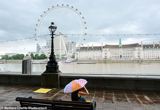 Downpours in London yesterday as a person sits across the Thames from the London Eye