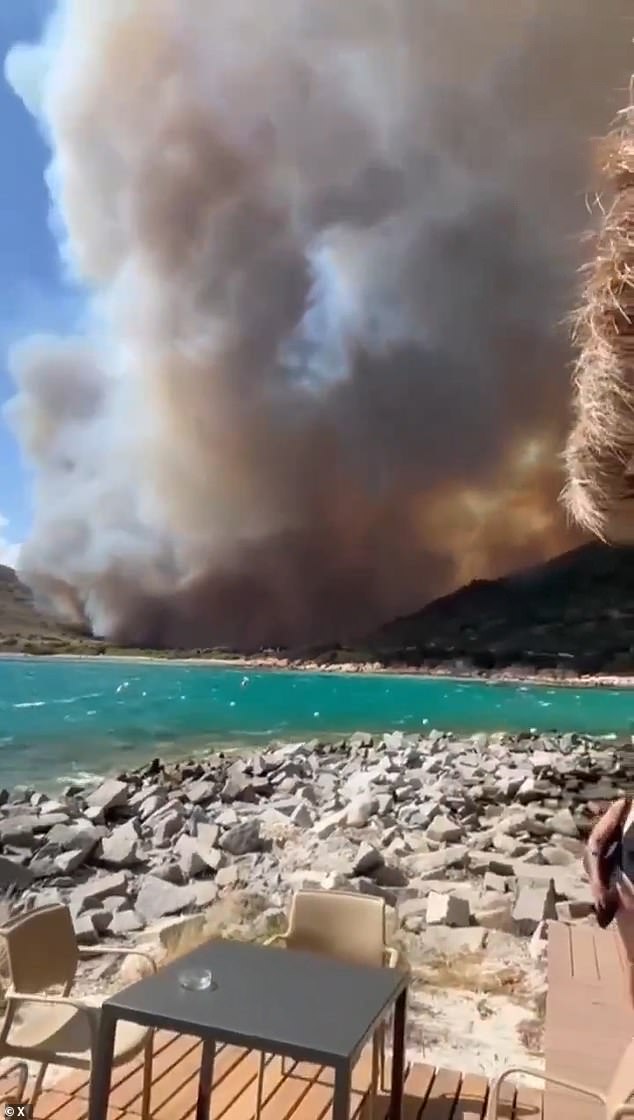 Thick smoke could be seen emanating from the wooded area as beachgoers enjoyed the sun in Sardinia