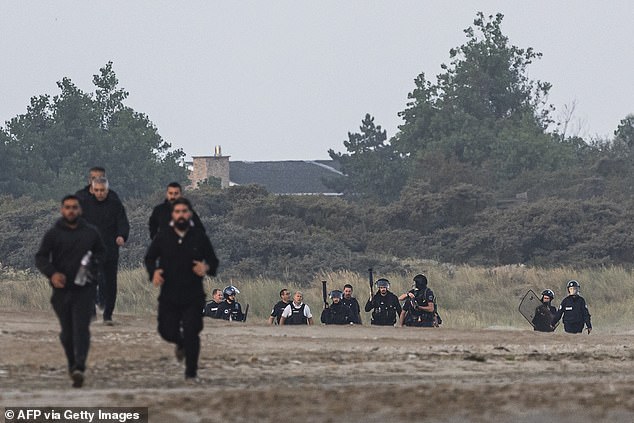 French police officers have been spotted idly watching on as a group of migrants attempted to cross the Channel in a small boat