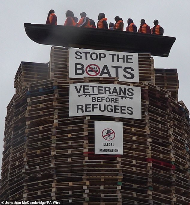 Effigies of lifejacket-wearing migrants in boats have been placed on a village bonfire in a display condemned by critics as 'sickening' and 'racist'