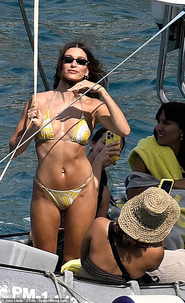 Hailey Bieber wowed in a skimpy bikini as she soaked up the sun in Majorca on Wednesday after hitting back at 'losers' who fuelled marriage trouble rumours