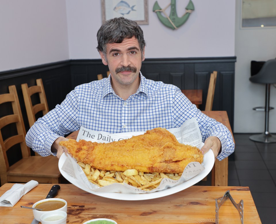 Man holding a large plate of fish and chips.