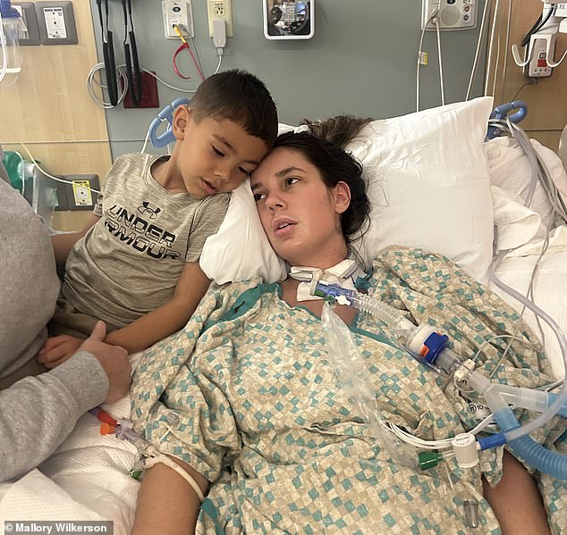 Pictured: Mallory Wilkerson lies in a 'waking coma' after being struck with a rare autoimmune condition. She couldn't communicate with her son, Beckham, five, who would try and comfort her by snuggling close in the hospital