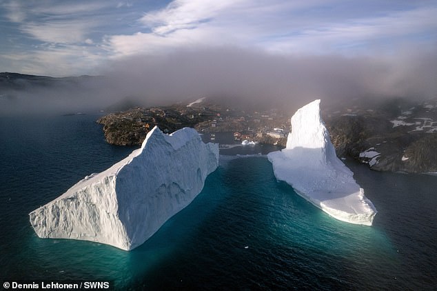Incredible images show a huge iceberg drifting dangerously close to the shore in Greenland