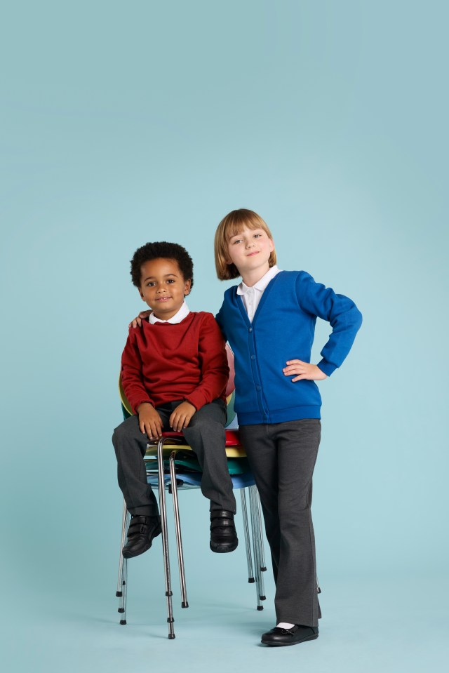 Two schoolchildren, one sitting on a stack of chairs, the other standing behind.
